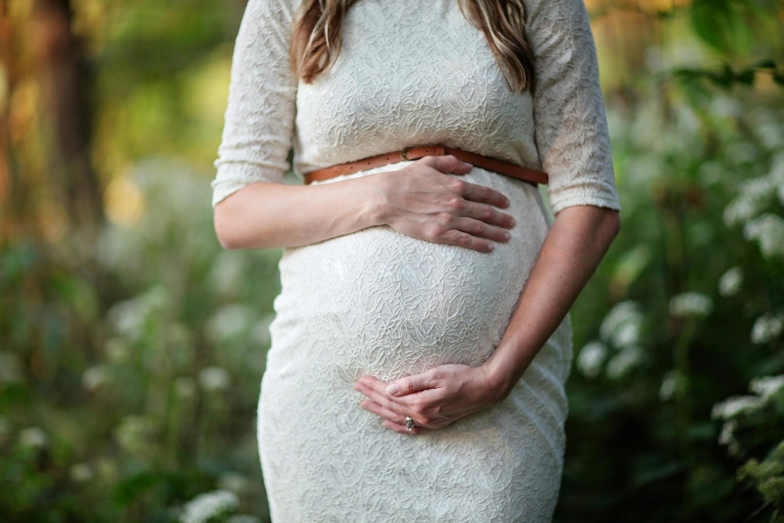 A woman in white holding her bump