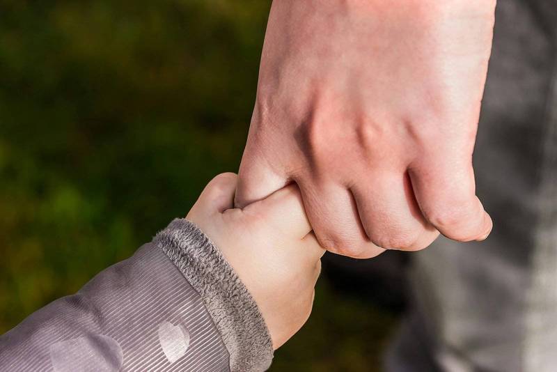 A baby holding her father's finger