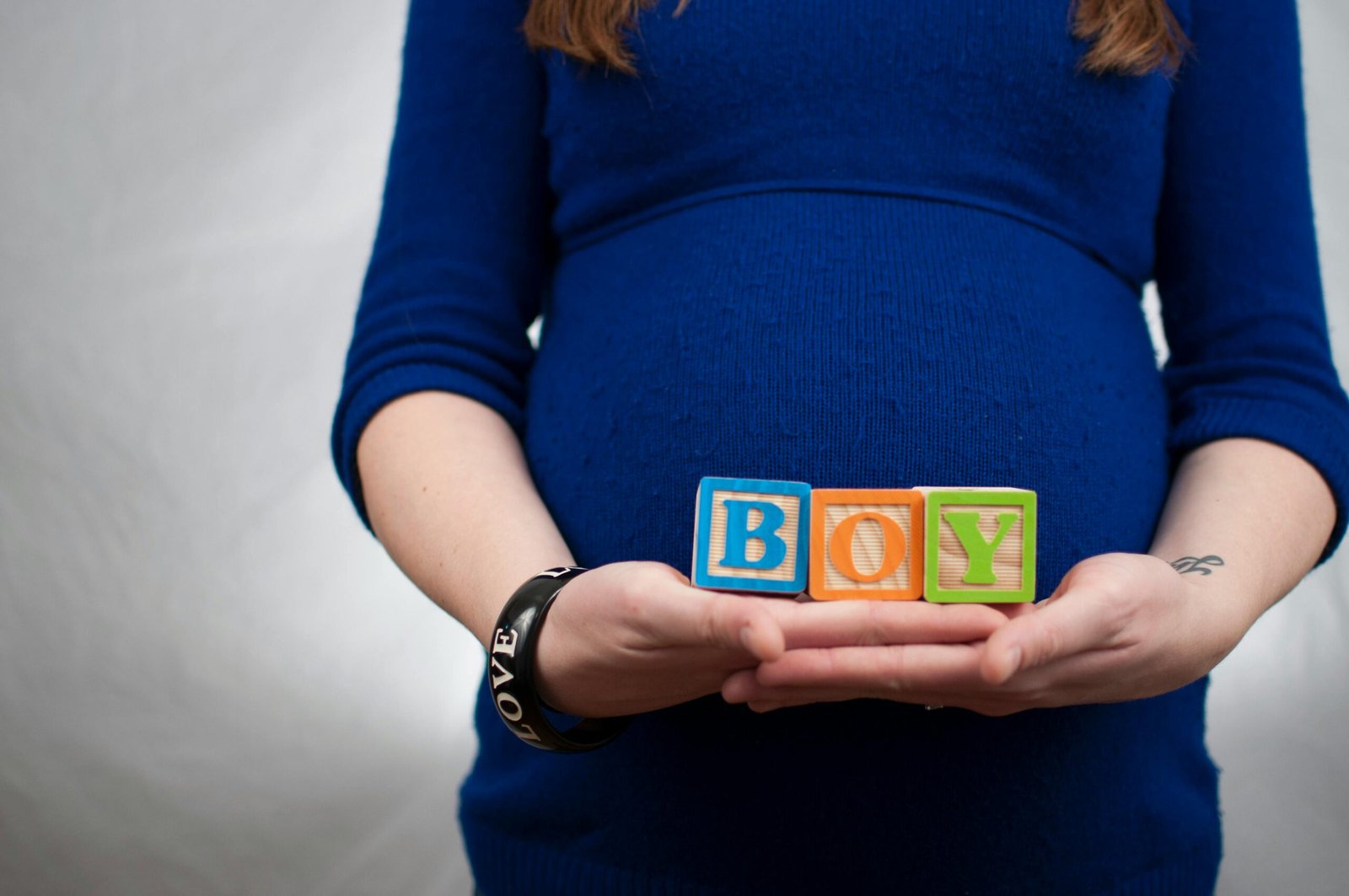 A pregnant holding a sign with the word "BOY"
