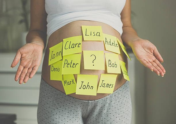 Photo of pregnant woman with child names on belly