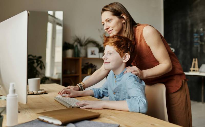 A mother helping her son on the computer