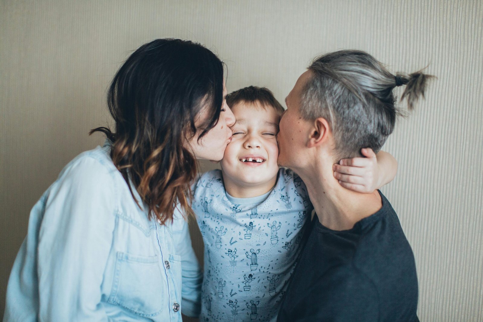 Two parents kissing their child on the cheek