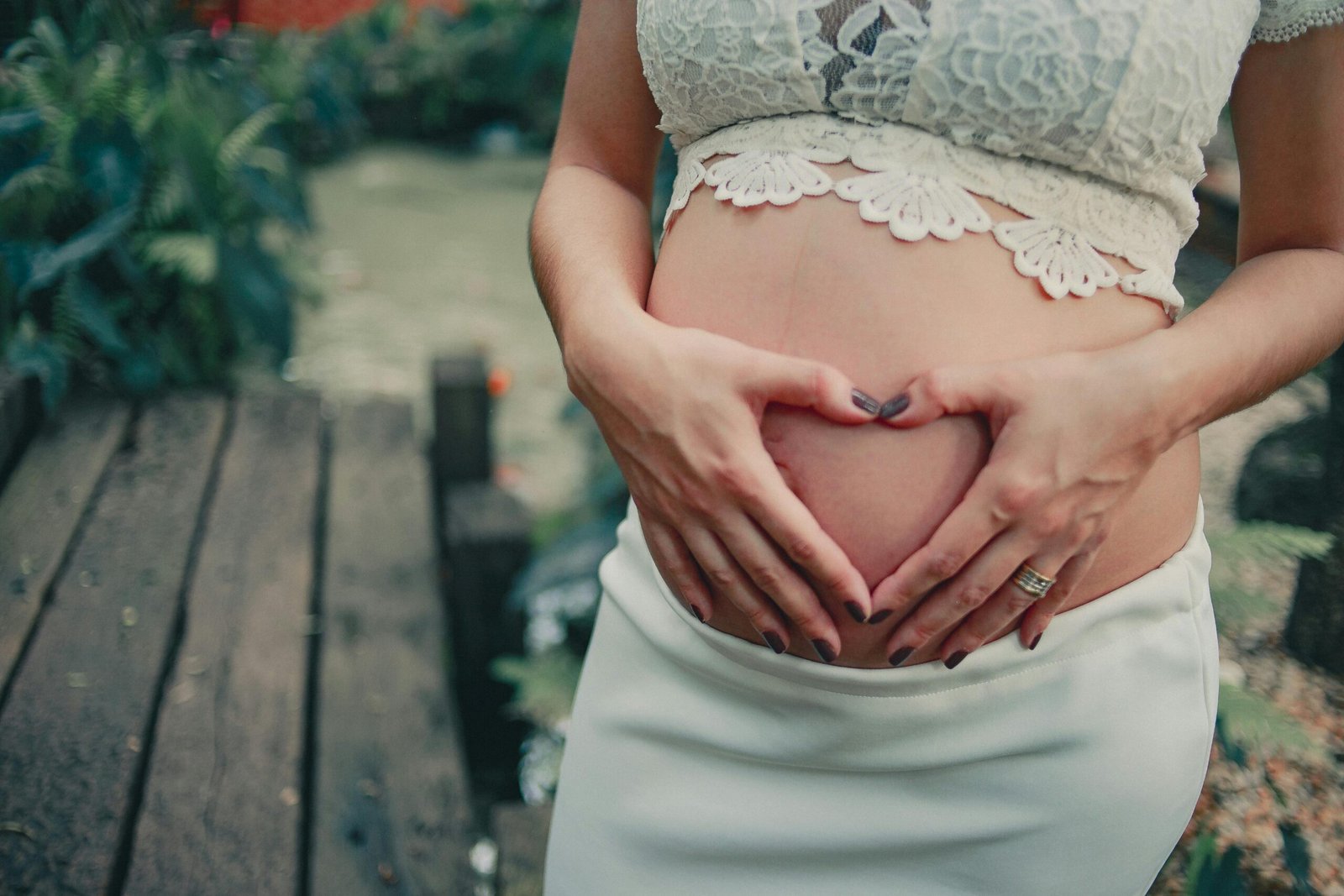 A woman forming a love shape on her belly with her hands.